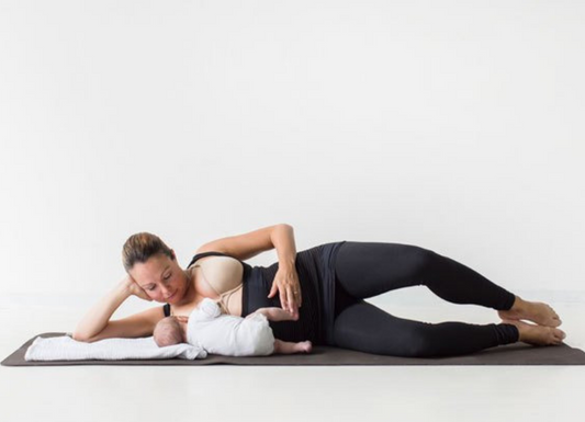 women_on_mat_wearing_abdominal_wrap_doing_postnatal_exercises_with_baby_beside_her